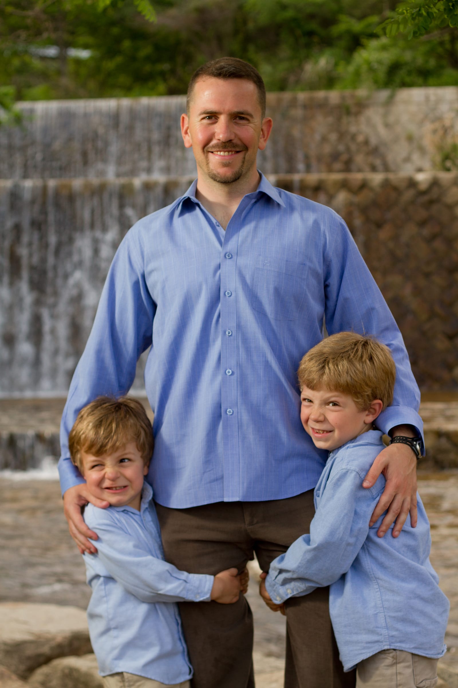 Father standing with two sons near a waterfall