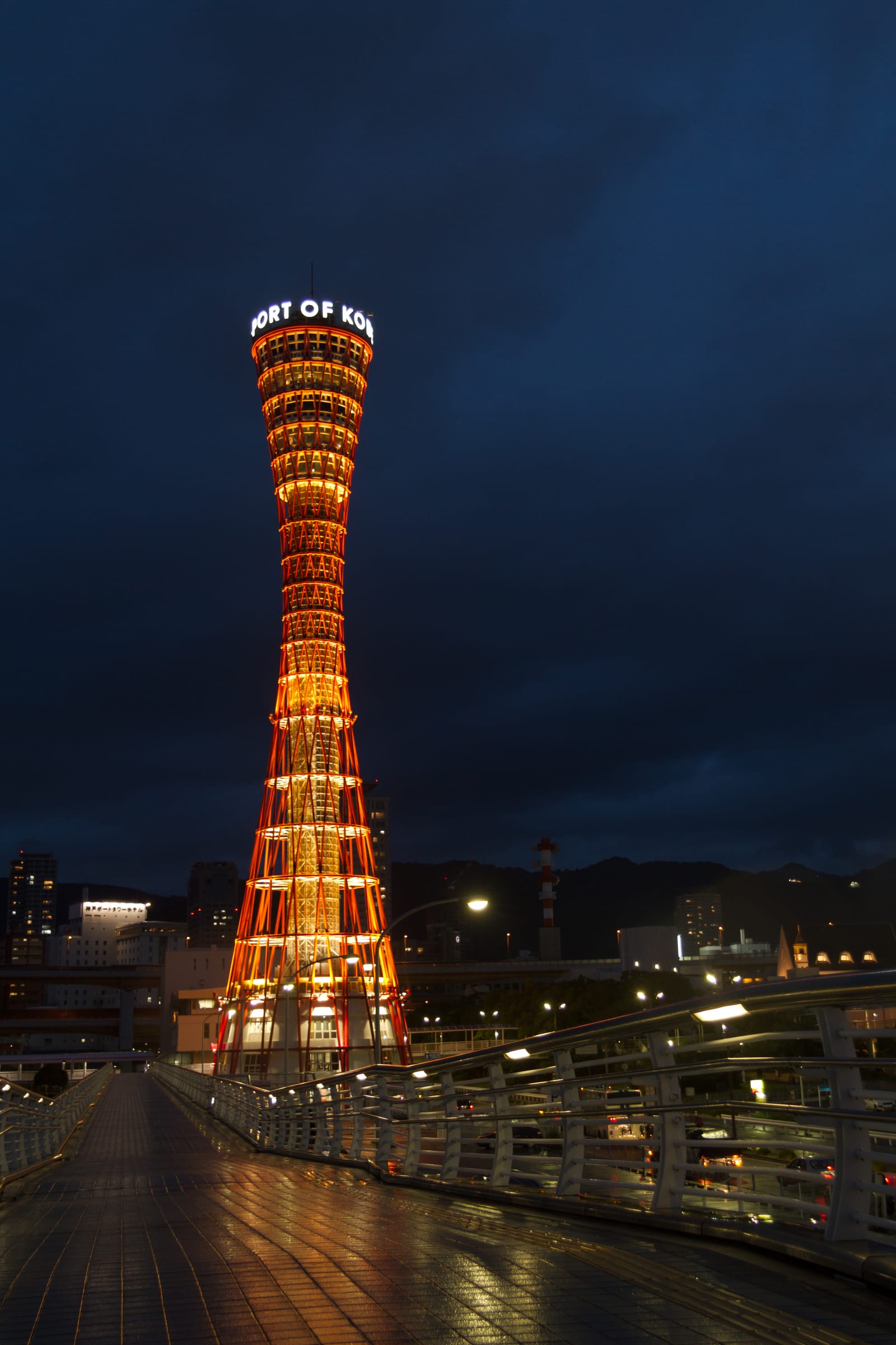 Kobe tower illuminated at night against the city skyline